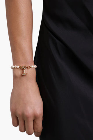 Model wearing the Aleksa bracelet by Vivienne Westwood in gold, featuring baroque pearls and a crystal-embellished orb.